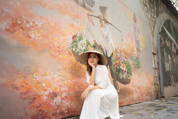 Portrait of Asian Vietnamese woman with Vietnam dress and straw hat with Graffiti in Hanoi, vietnam...
