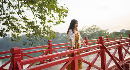 Portrait of Asian Vietnamese woman travel in The Red Bridge in public park garden with trees in Hoan Kiem Lake in Downtown Hanoi. Urban city, Vietnam..