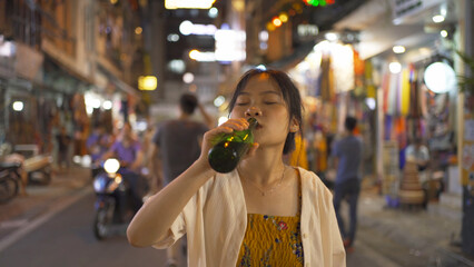 Drunk alcoholic woman Asian Vietnamese woman travel at night, drinking beer in market. People walking street fair in Hanoi city, Vietnam. Retail shops