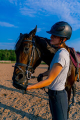 A helmeted rider feeds her beautiful black horse from her hand in the equestrian arena during a...