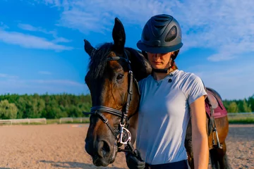 Foto op Canvas A helmeted rider leads her beautiful black horse by the harness in the riding arena during a horseback ride © Guys Who Shoot