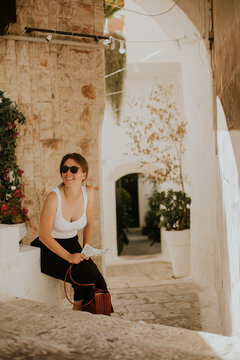 Fototapeta Female tourist with paper city map on narrow streets of Ostuni, Italy