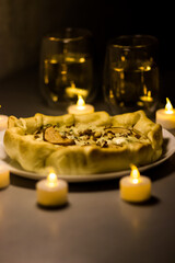 Tart with pear and gorgonzola cheese surrounded by candles. Romantic dinner. Exquisite wine appetizer