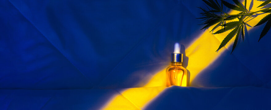 Oil tincture with cannabis in moonlight at night on bed with hemp branch