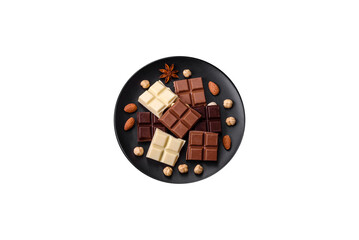 A mix of several types of delicious sweet chocolate broken into cubes on a black plate