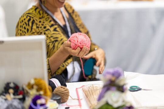 An elderly woman holds a skein of yarn in her hand