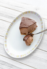 Porción de mousse de chocolate casero sobre plato blanco y mesa de madera blanca