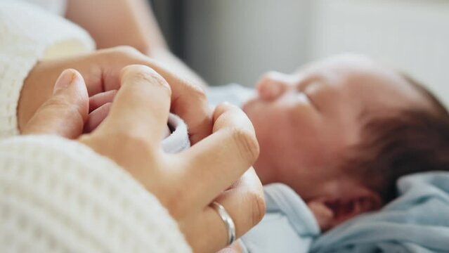 The newborn is holding a finger of mother on a white background. Healthcare, pediatrics. Newborn. Unrecognizable family admiring their newborn baby at hospital with mother at post natal department