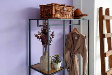 Stylish coat rack near lilac wall in hall