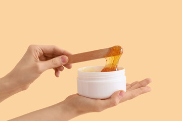 Female hands holding sugaring paste on beige background