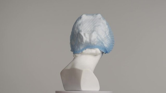 Closeup shot. Ancient marble bust statue of roman era woman in bouffant and face mask spins on a platform. Isolated on grey background. HDR BT2020 HLG Material.