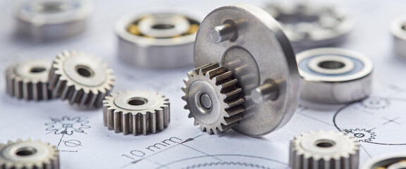 Planetary gearbox and metal gears close-up. Background with drawings of the mechanism and bearings.
