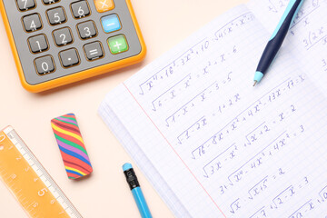 Copybook with maths formulas, calculator and stationery on beige background