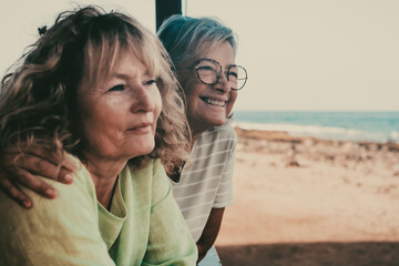 Happy couple of senior and middle age women in good mood looking at horizon over sea. Two female friends in outdoors appreciating freedom and relax