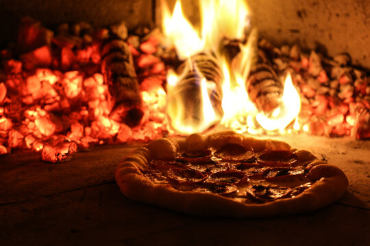 Pizza assando em forno a lenha.