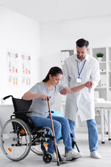 Fototapeta premium Male physiotherapist helping young woman to stand up in rehabilitation center