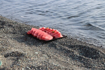 Watermelon, strawberries and raspberries on the sand by the sea