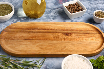 Wooden kitchen board and fresh spices on color background, closeup