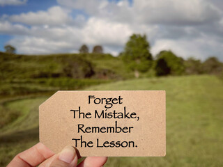 Motivational and inspirational wording. Forget The Mistake, Remember The Lesson written on a notepad. With blurred styled background.