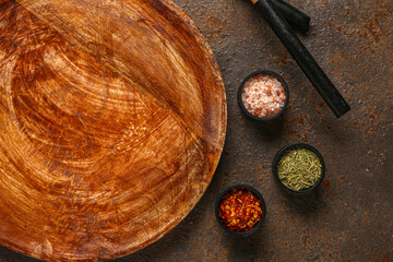 Wooden kitchen board and bowls of spices on grunge background, closeup