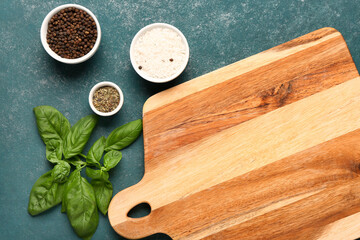 Wooden cutting board with aromatic spices on color background, closeup