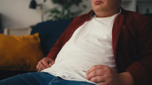 Closeup of overweight man holding his belly, worried about obesity consequences
