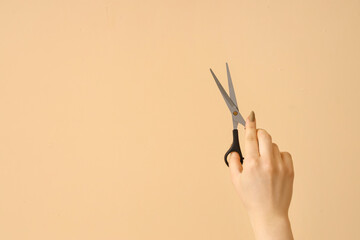 Female hands with scissors on beige background