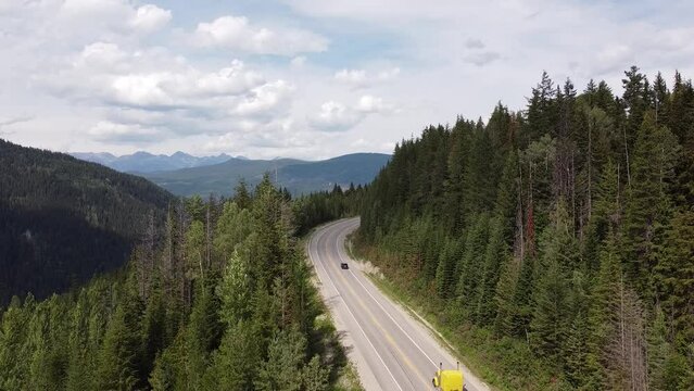 Cars Driving on Highway Road - Still Video - Rocky Mountains British Columbia Canada. Cars passing by on a scenic road with trees and mountains surrounding them.