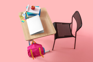 Modern school desk with backpack, laptop and stationery on pink background