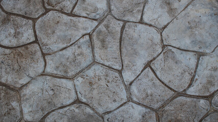 A gloomy, colorless stone floor in a park or a dull, layered wall of large stones can be used as a background image or wallpaper.