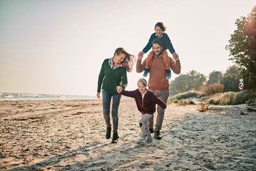 Young happy caucasian family walking the beach during winter