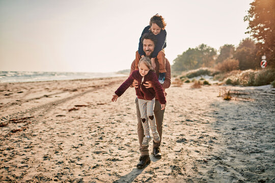 Young father walking on a winter beach with his two young children