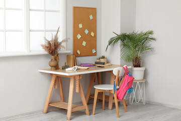 Modern school desk with stationery in room near white wall