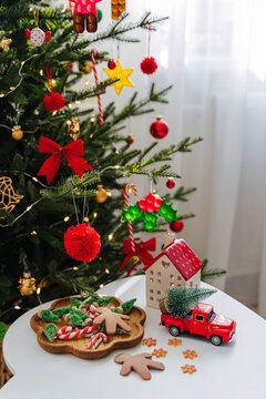 Christmas holidays. Little houses, toys and christmas decorations on the table next to the Christmas tree. Holiday Activity for Kids. Merry Christmas and Happy Holidays!