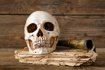 Human skull with old manuscripts and spyglass on brown wooden background