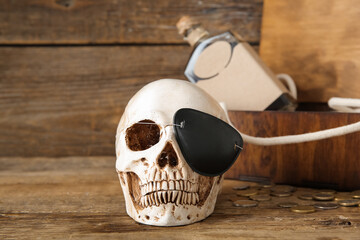 Chest with human skull, pirate eye patch and bottle of rum on brown wooden background