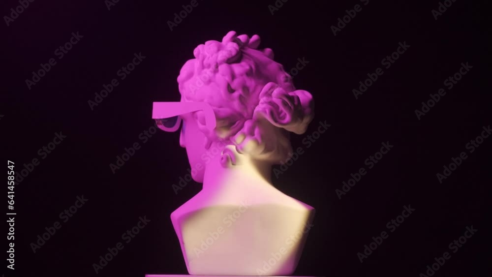 Wall mural Closeup shot. Ancient marble bust statue of roman era woman in 3d glasses spinning round on a platform in neon light. Isolated on black background. HDR BT2020 HLG Material.