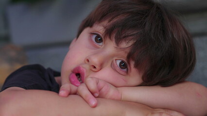 Close-up of bored child drooling and gazing in the distance, daydreamin and lost in thought,...