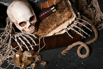 Pirate chest with travel equipment, golden nuggets, human skull and net on black background