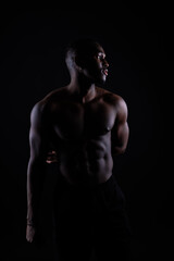 Close-up muscles of african american handsome body builder naked torso on black studio background