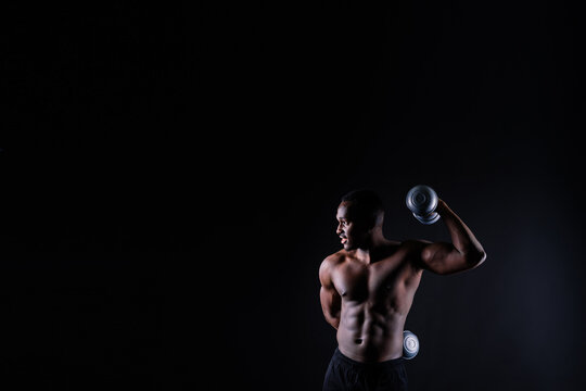 Close-up muscles of african american handsome body builder naked torso on black studio background