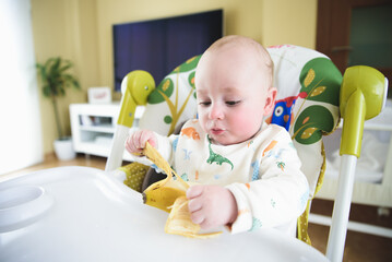 baby sitting in his chair eating banana