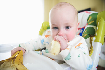 baby sitting in his chair eating banana