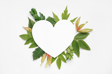 Blank heart shaped card and green leaves on white background