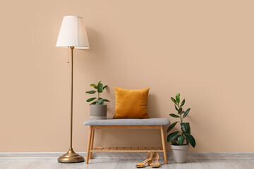 Interior of stylish room with soft bench and female shoes near beige wall