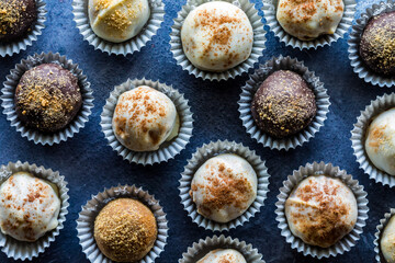 Many pumpkin spice truffles with different toppings in paper cups.