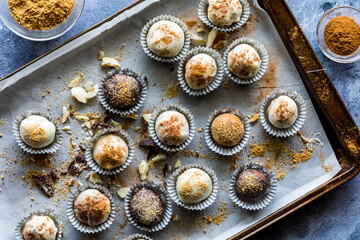 Pumpkin spice truffles in paper cups on a messy parchment paper baking sheet.