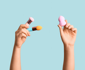 Female hands with different makeup sponges on blue background