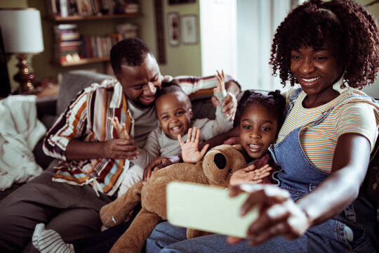 Young african family taking a selfie with a smart phone on the couch in the living room
