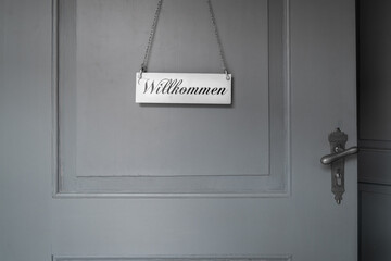 Ausschnitt einer Tür aus Holz mit grauer Farbe gestrichen im oberen Bereich hängt ein helles...